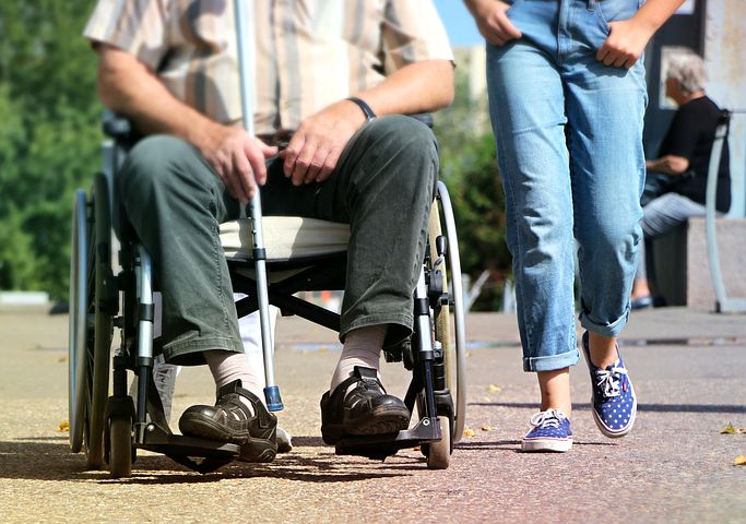 disability support worker walking next to a man on a wheelchair